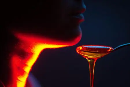 Žlica medu ki pomirja razdraženo grlo ponazarja kako ublažiti kašelj ponoči