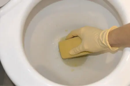 prikaz kako očistiti dno wc školjke s pomočjo plovca za odstranjevanje trdovratnih madežev
