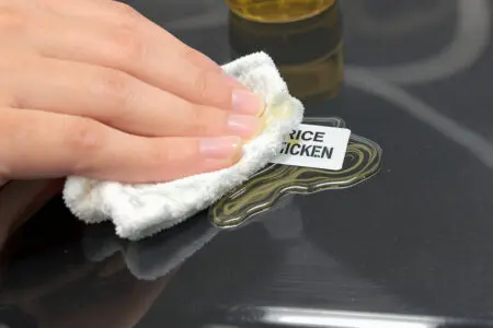 prikaz kako odstraniti lepilo iz plastike z uporabo olja in krpe za raztapljanje lepljivih ostankov